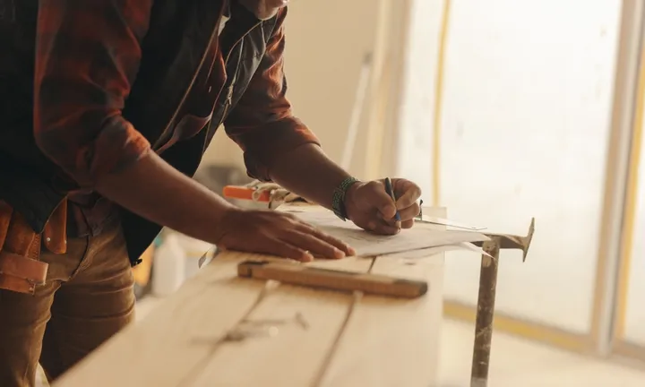 Construction,Expert,Attentively,Marks,Blueprints,On,A,Kitchen,Counter,,Planning