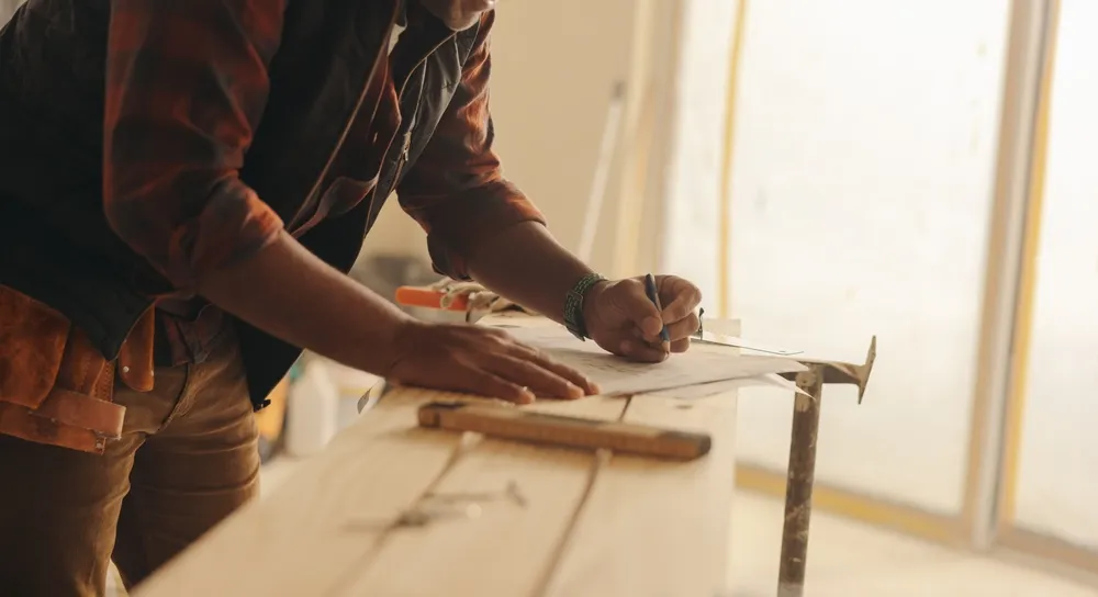 Construction,Expert,Attentively,Marks,Blueprints,On,A,Kitchen,Counter,,Planning